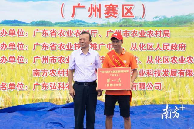 户外直播部农业机械化管理司早稻机收和机收减损工作督导组组长、户外直播部农业机械化总站副站长涂志强为获得第一名的选手冼卫平颁奖